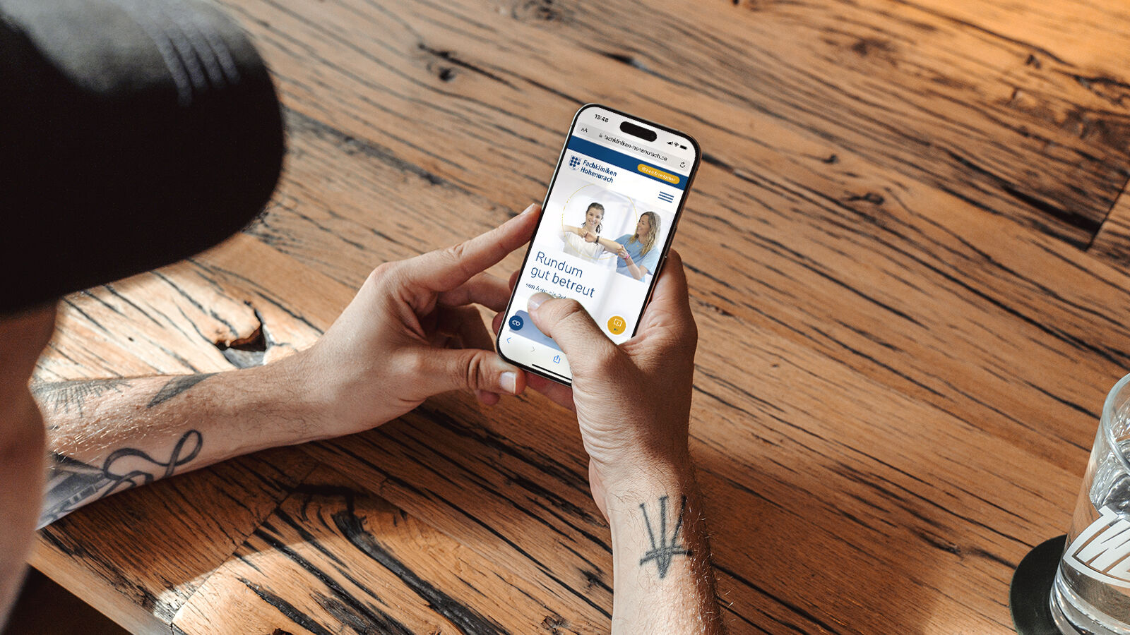 Zwei Hände halten ein Smartphone mit der mobilen Website der Fachkliniken Hohenurach.