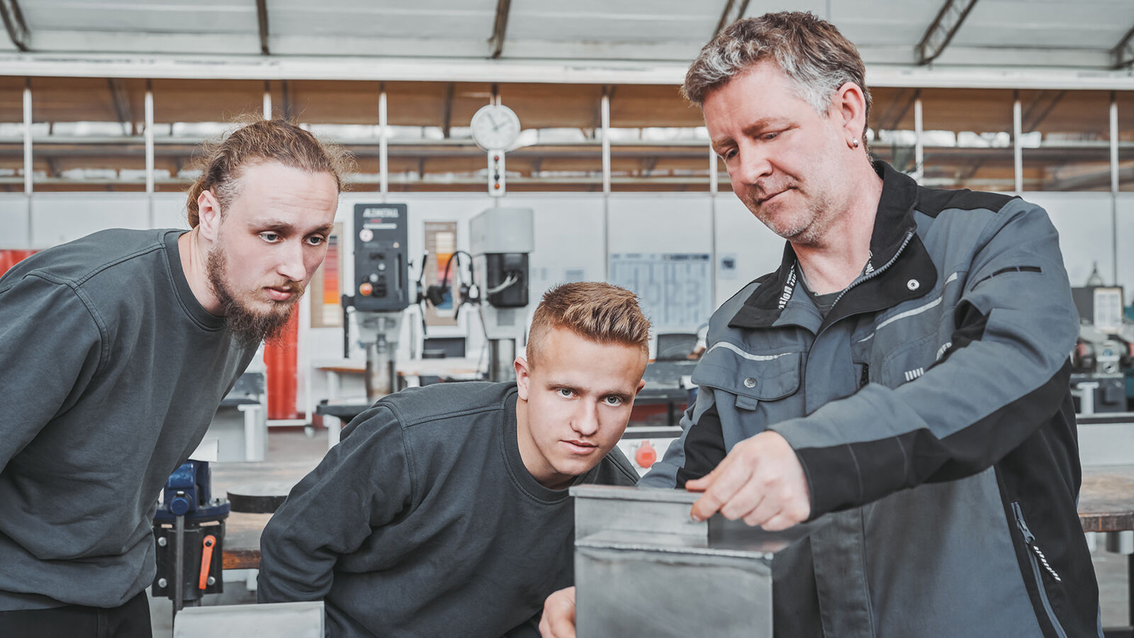 Employer Branding für GARTNER: ein Ausbilder zeigt zwei Auszubildenden in der Lehrwerkstatt ein Blechwerkstück.