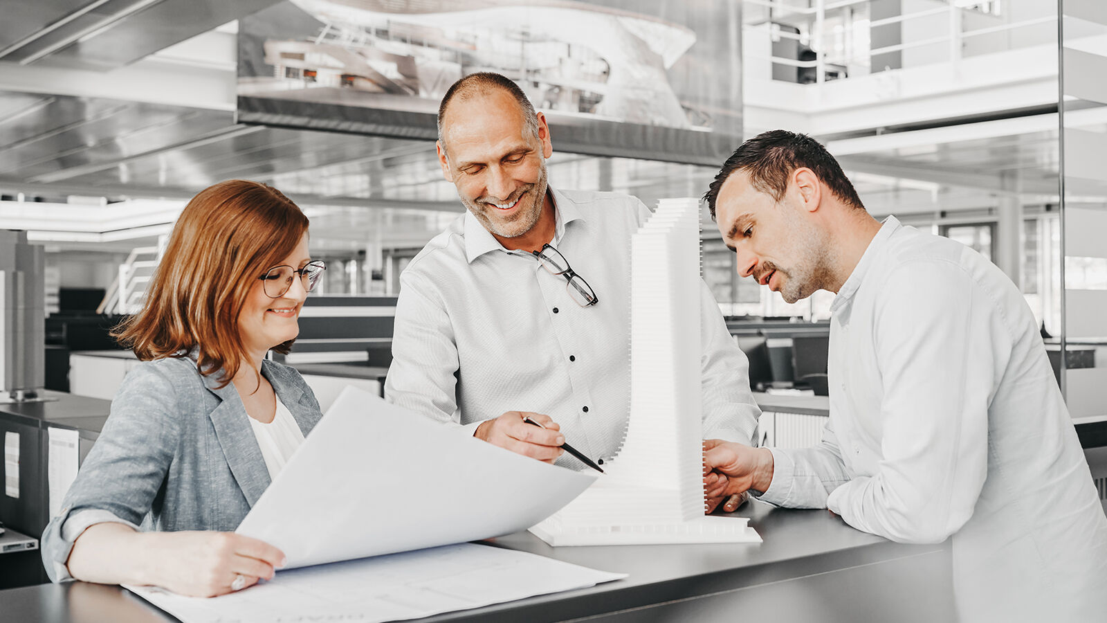 Employer Branding für GARTNER: drei Beschäftigte begutachten am Tisch ein weißes Fassadenmodell.