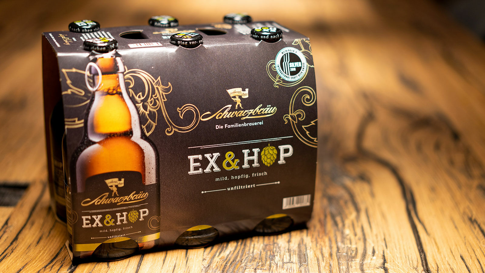 Sixpack Ex & Hop von Schwarzbräu auf einer Holzplatte.