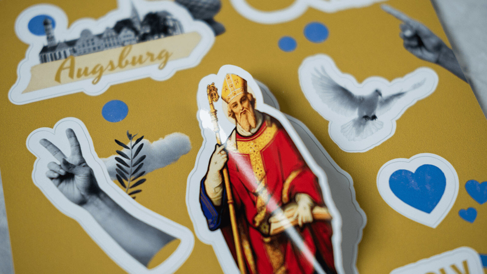 Stickerbogen von Uli & Du mit dem heiligen Ulrich, einer Taube, dem Augsburger Rathaus und einem Peacezeichen.