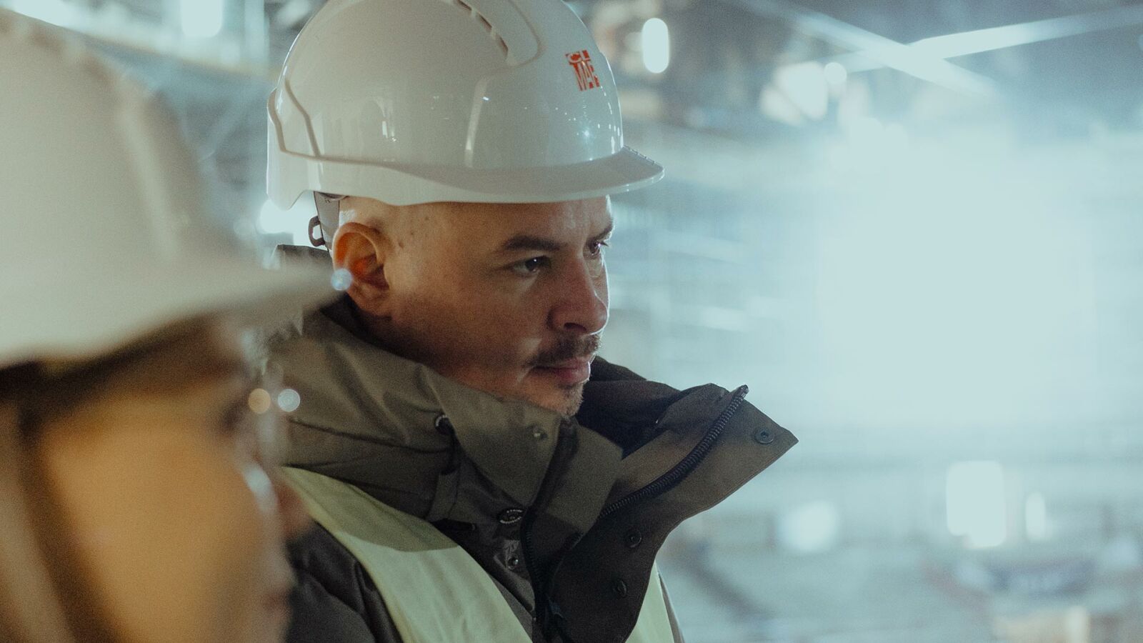 Ein Mitarbeiter von CL MAP mit Helm und Gehörschutz auf einer Baustelle im Gegenlicht.